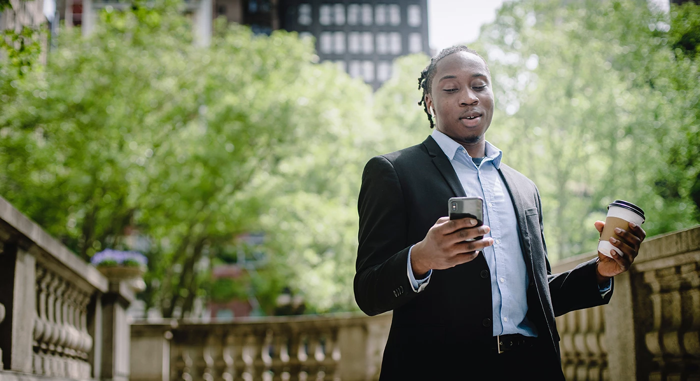 Person looking at their phone while holding a coffee